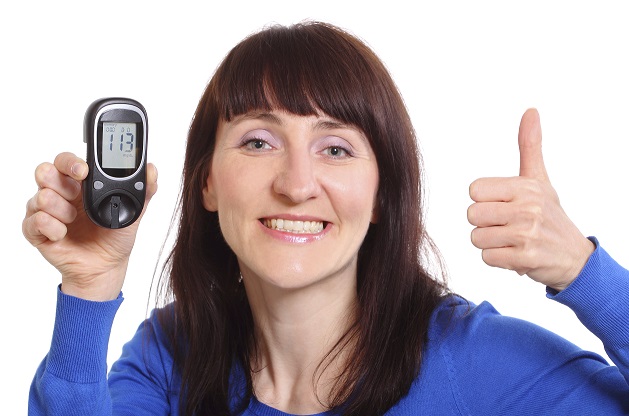 Smiling woman with glucose meter showing thumbs up