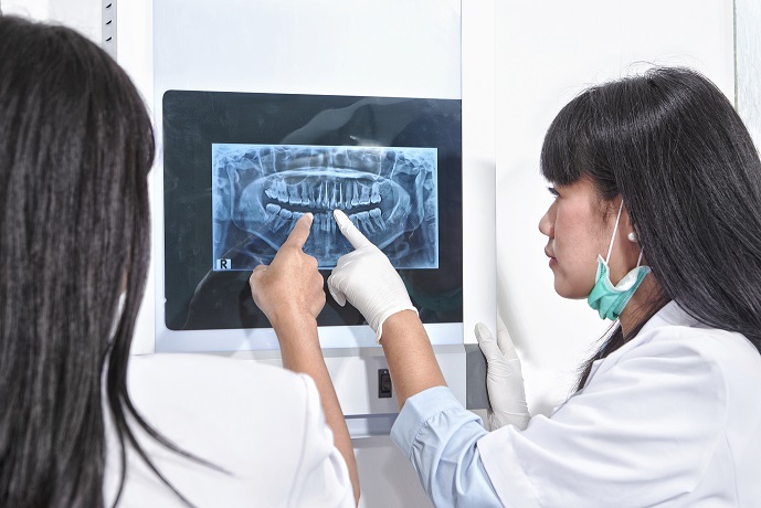 Young female dentist examining patient teeth X Ray