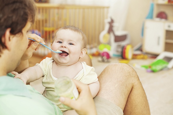 father feeding his cheerful baby
