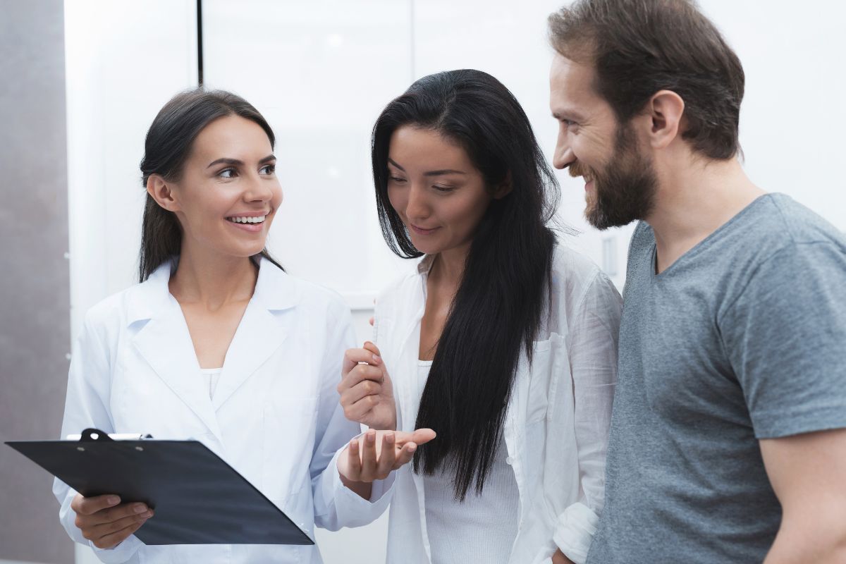 Three people reviewing documents together in a professional indoor setting with white walls.