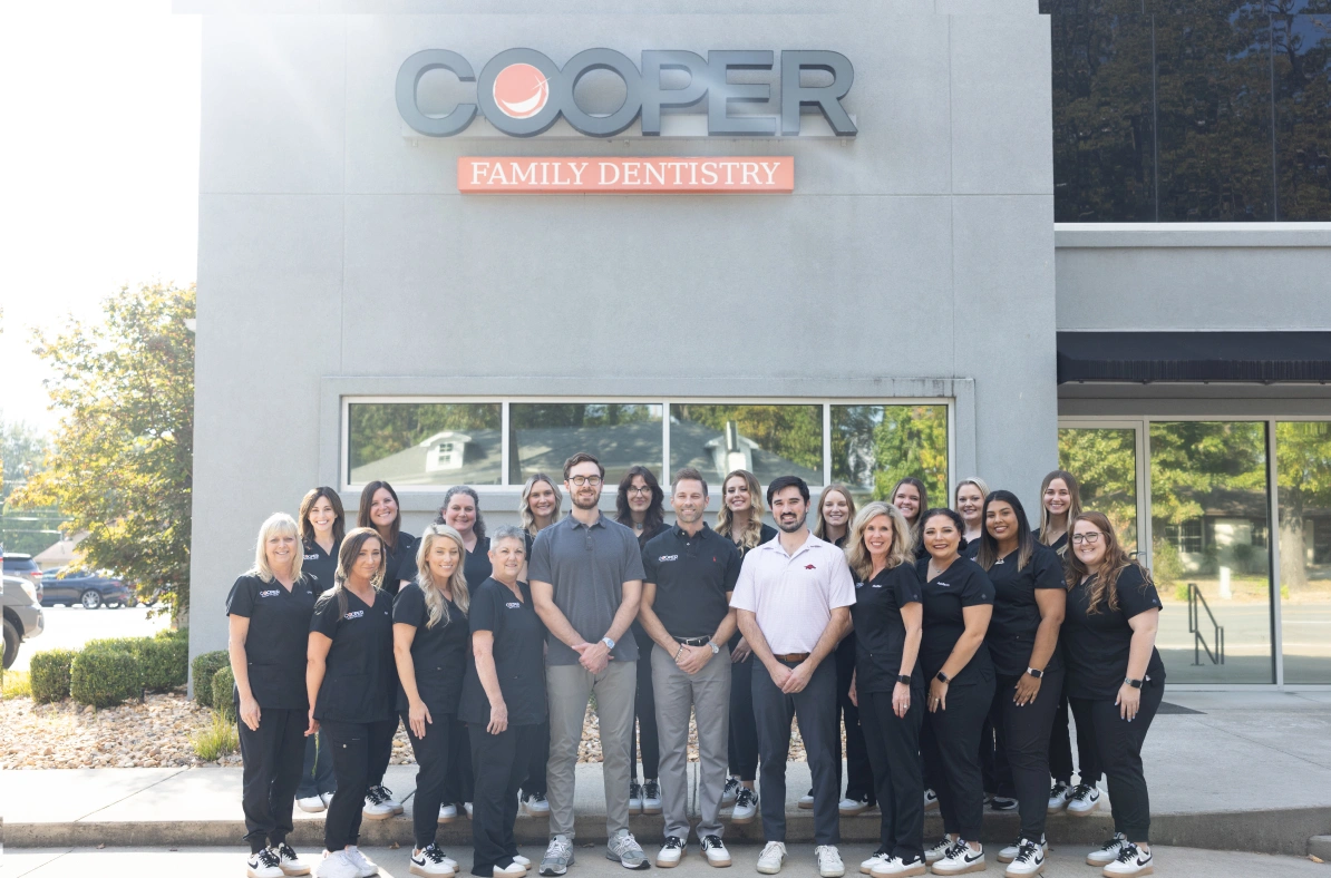 Large group of people in black shirts standing together outside a Cooper family business building.