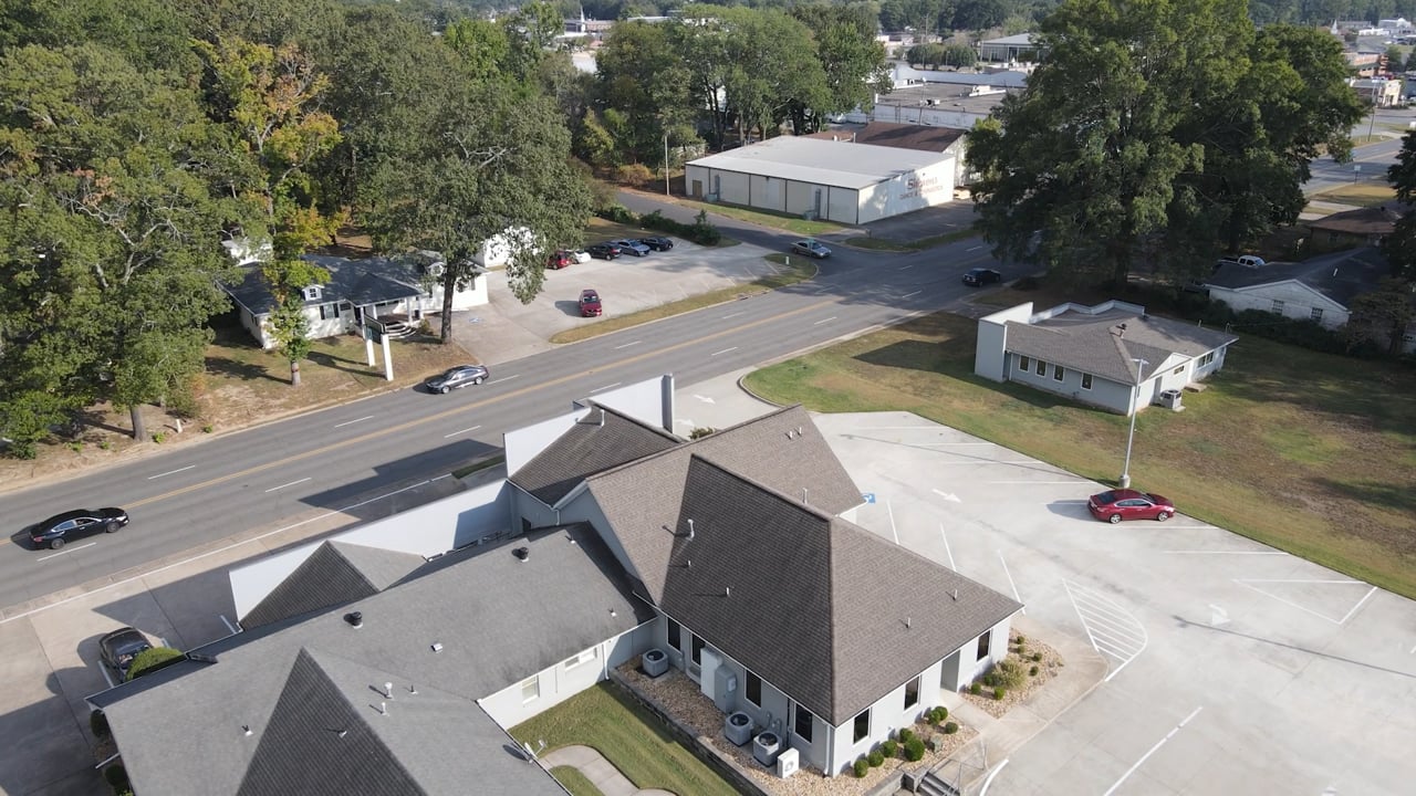 Aerial view of modern residential neighborhood with dark-roofed houses and tree-lined streets.