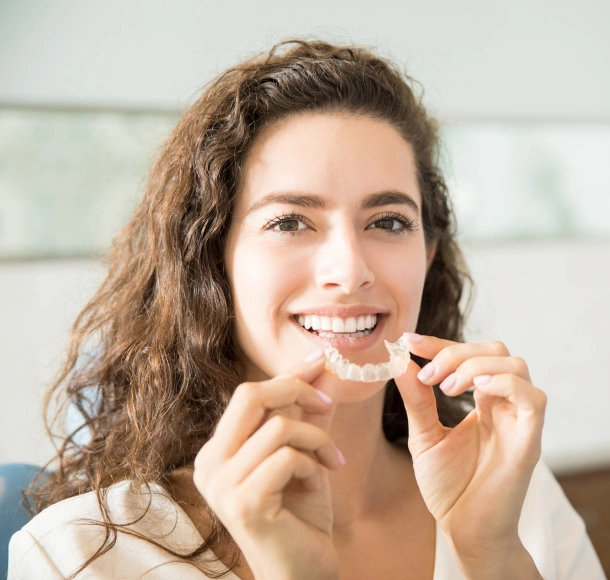 Smiling woman breaking cigarette in half indoors, representing smoking cessation.